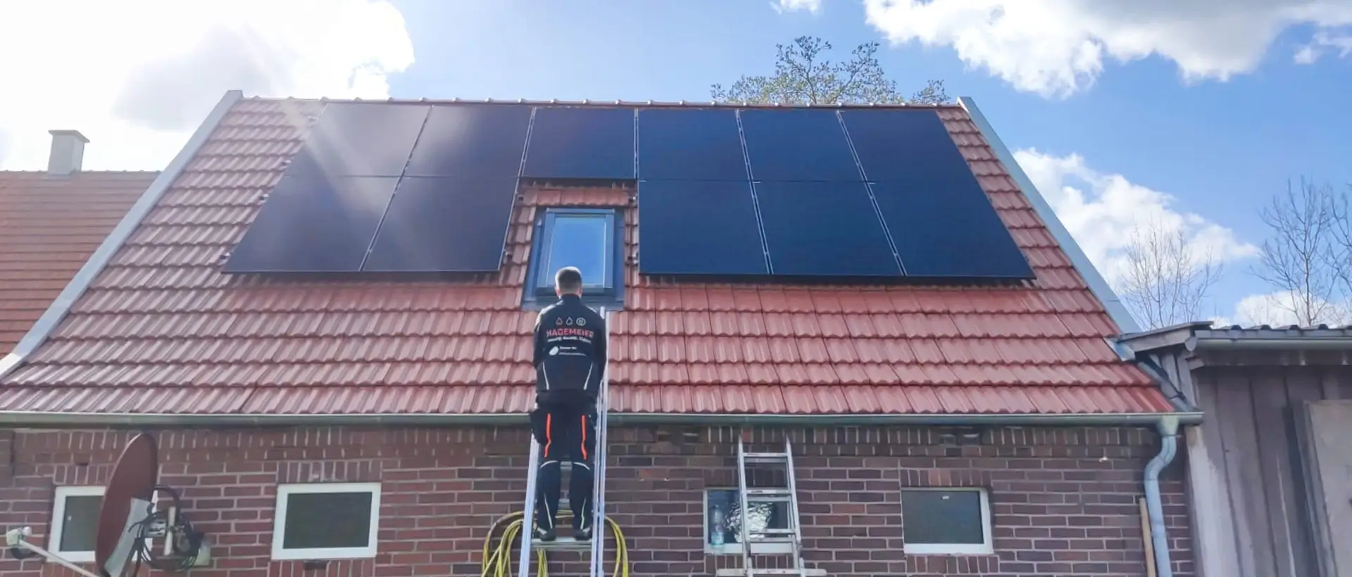 Hagemeier Mitarbeiter auf der Leiter vor Photovoltaikanlage auf dem Dach eines Hauses